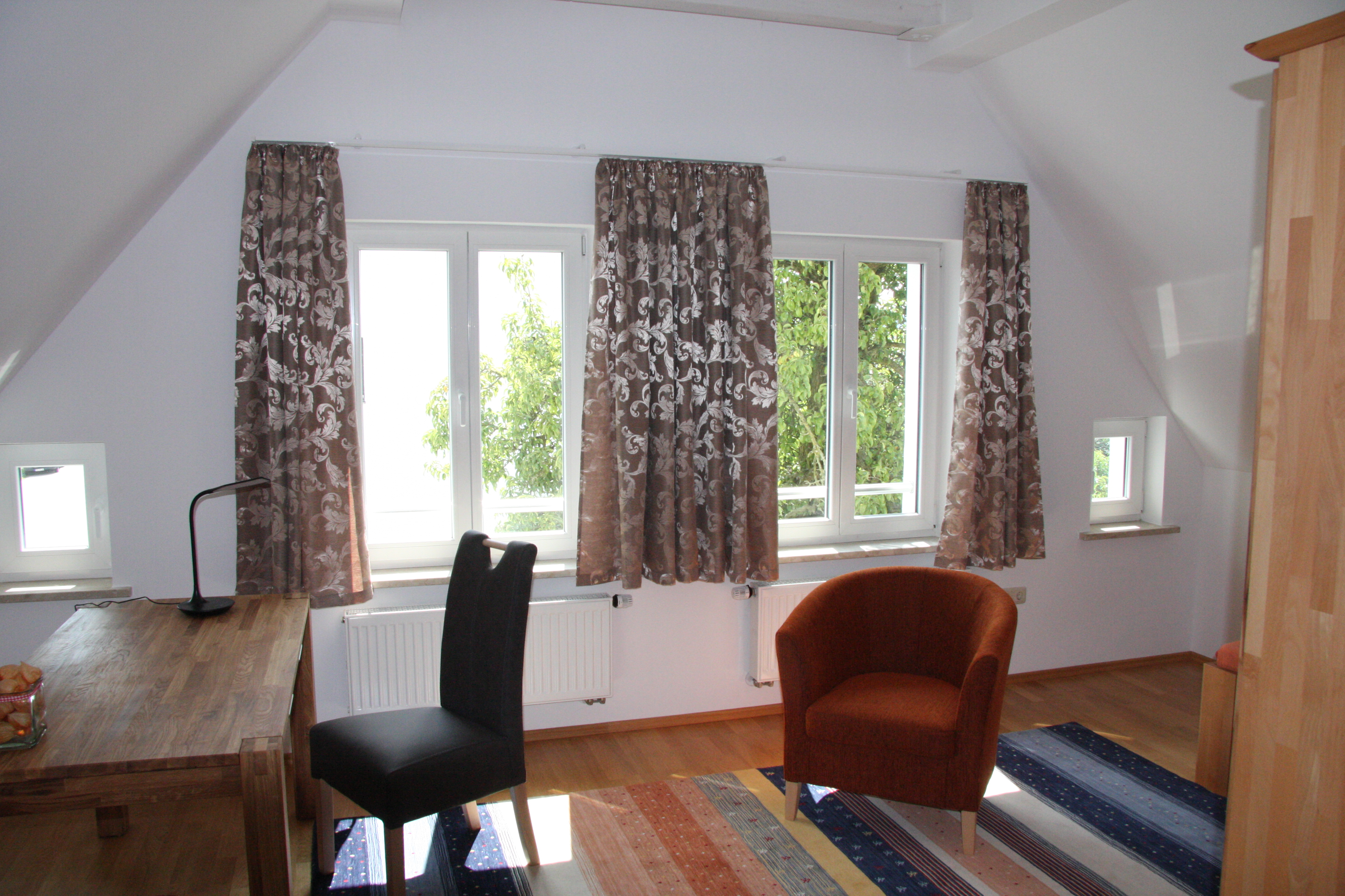 Helles möbliertes Dachgeschoss-Zimmer mit drei Fenstern und Blick ins Grüne in der Bachstraße in Schwandorf